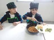 La imagen puede contener: 2 personas, personas sonriendo, personas sentadas, personas comiendo y comida